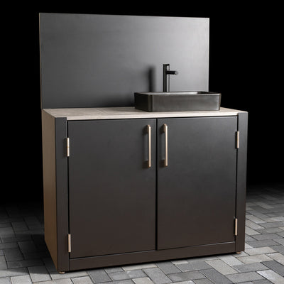 Outdoor sink unit faucet against a dark gray wall.